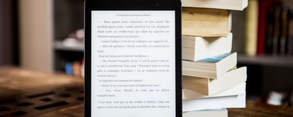 Une liseuse devant une pile de livres